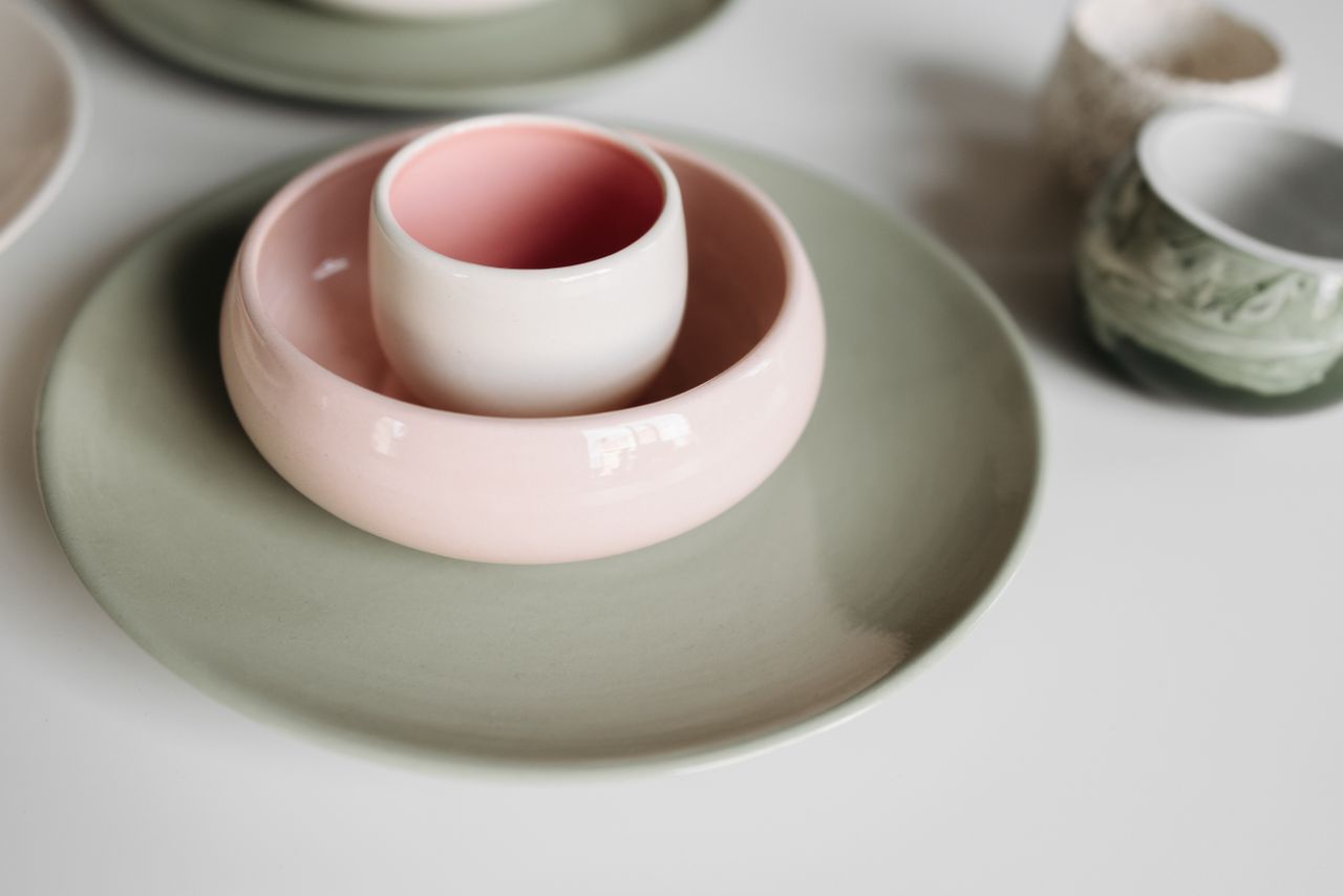 A close-up of colorful ceramic bowls and cups on a white table.