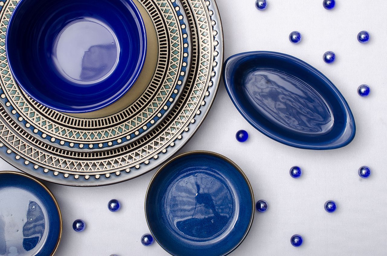 Stylish blue ceramic plates arranged on a white background in a flat lay setup.
